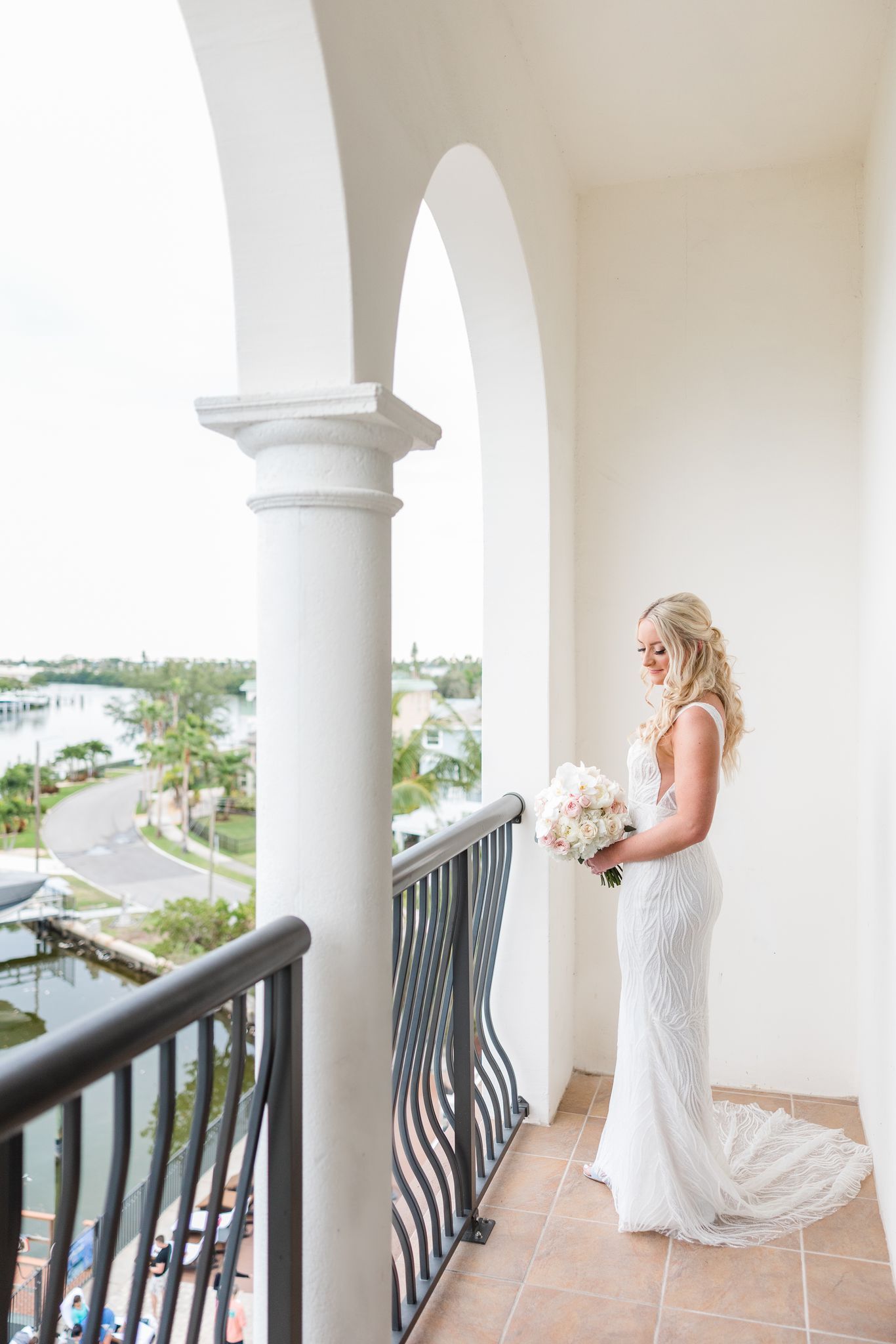 Pretty bride in her wedding dress standing on hotel balcony