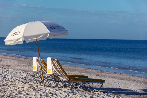 Two chairs and one umbrella on the beach outside of The Hotel Zamora