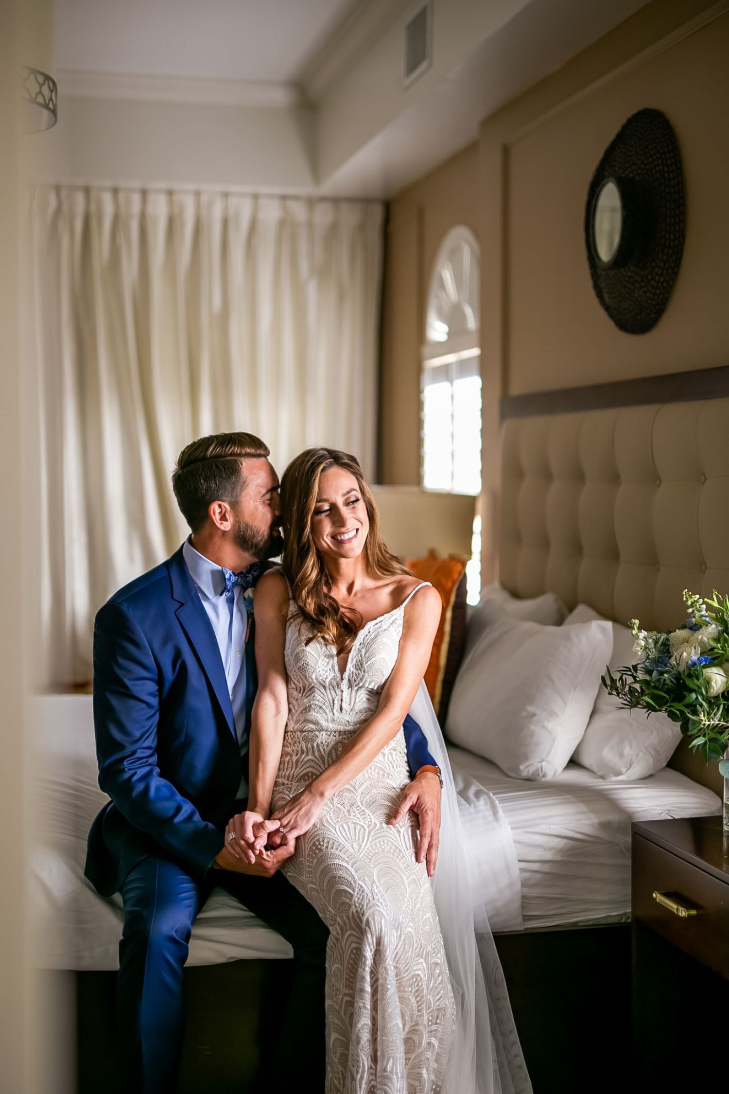 Couple getting ready for their wedding sitting on bed in The Hotel Zamora guest room