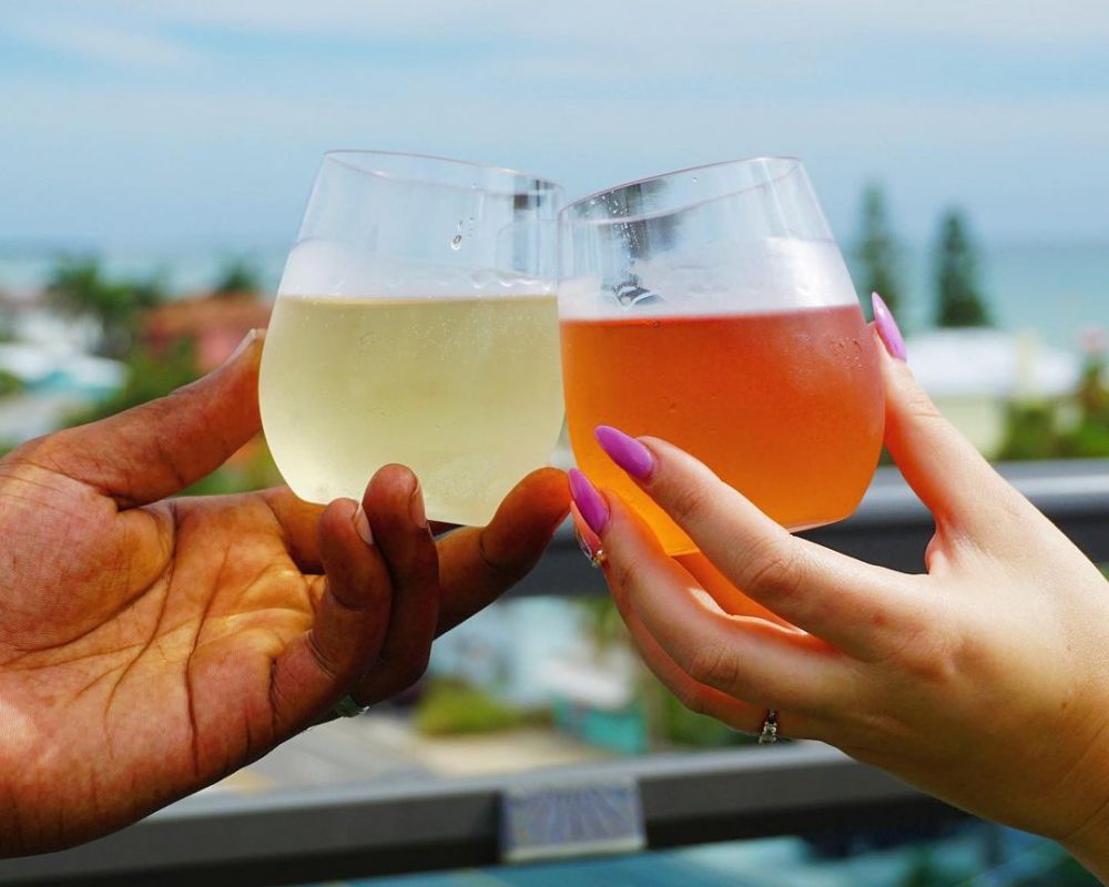 two people clinking their glasses with drinks together outside at The Hotel Zamora