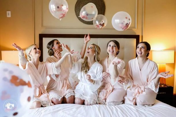 Bachelorette party with girls sitting on the bed in their hotel room throwing up balloons