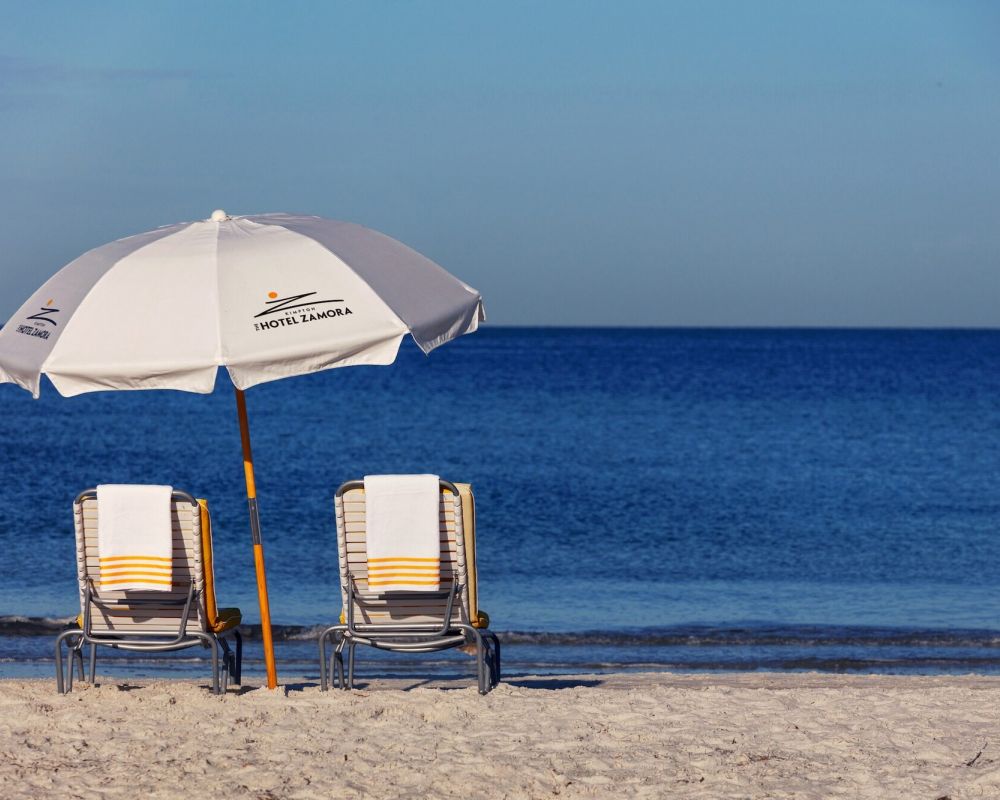 Two chairs and an umbrella on the beach overlooking the ocean